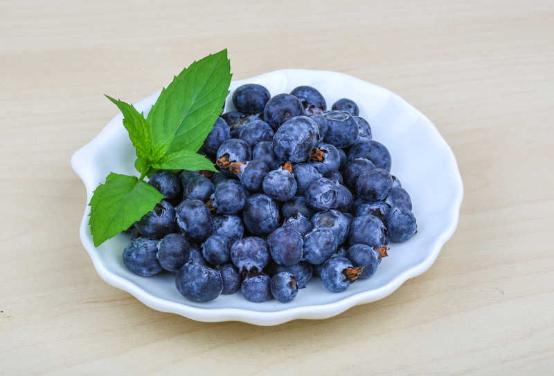 木桌上白盆里的新鲜蓝莓
