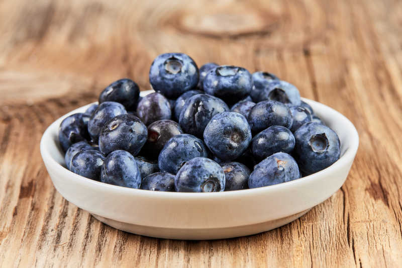 木桌上白盆里的有机蓝莓