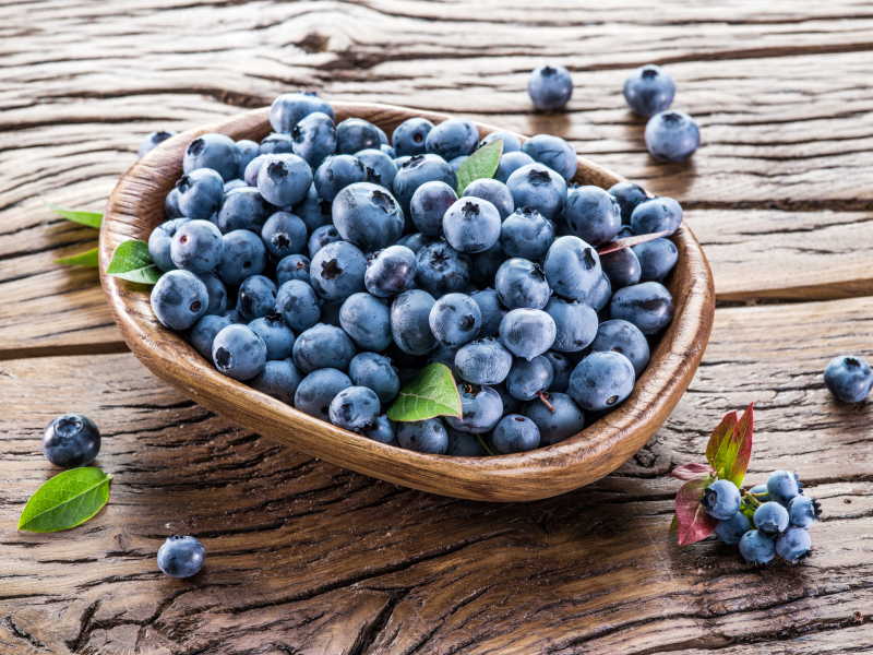 木制背景上的一盆新鲜蓝莓