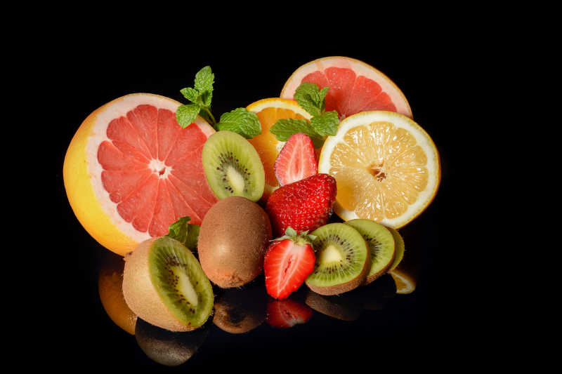 黑色背景下的草莓葡萄柚柠檬猕猴桃和橘子