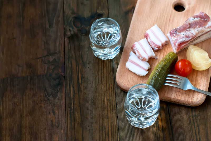 木桌上玻璃杯中的伏特加和蔬菜肉
