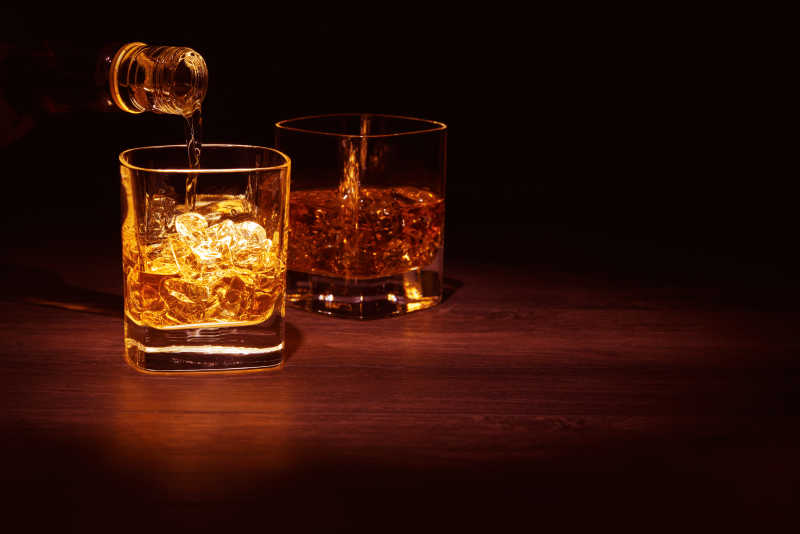 木桌上被灯打亮的两杯威士忌