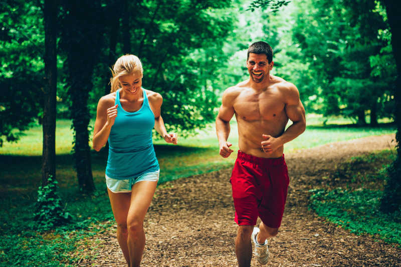 快乐的年轻夫妇在森林里慢跑