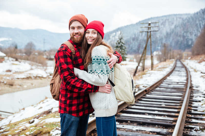 美丽的情侣站在铁路上拥抱的肖像