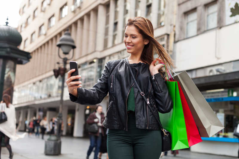 购物的美女在街头用手机自拍