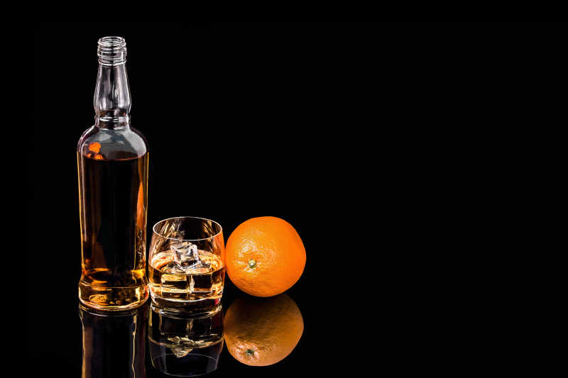 威士忌与冰和橙色在黑色背景上
