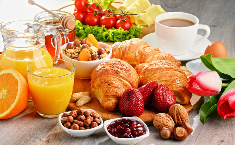 木桌上的丰富早餐和橙汁与水果
