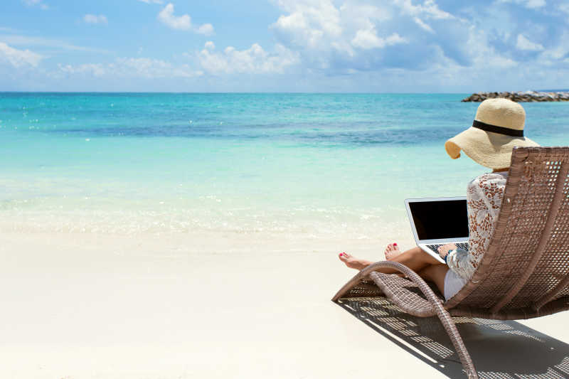 使用笔记本电脑的女商人在海滩上工作
