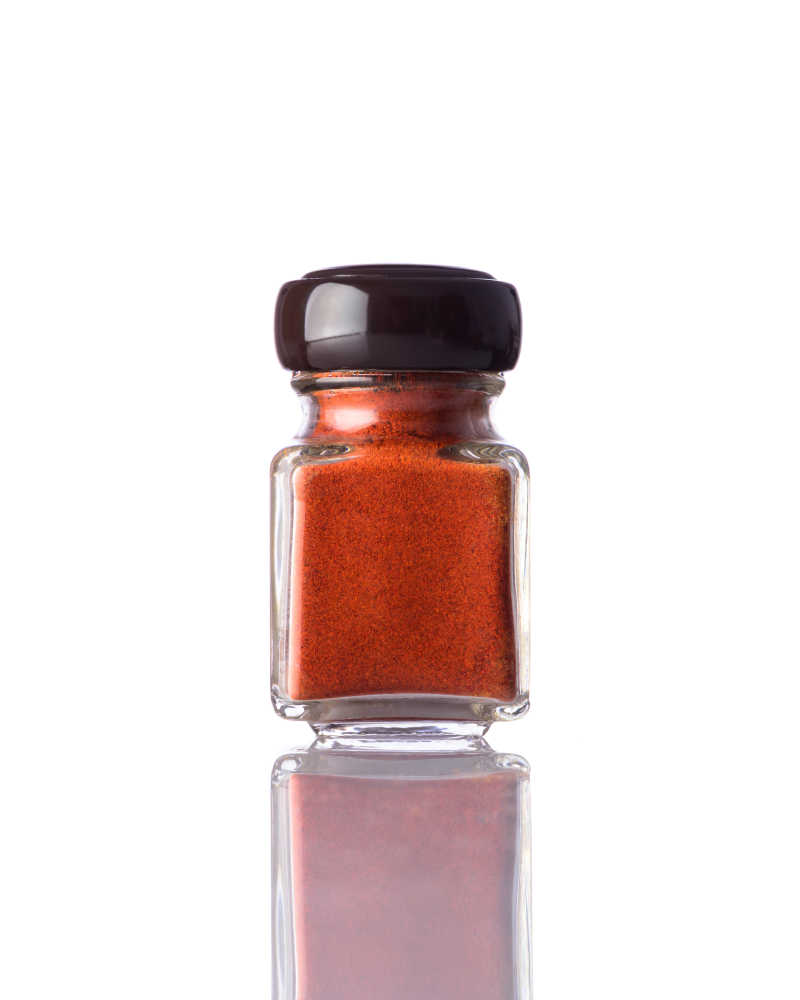 白色背景下罐子中的红辣椒粉