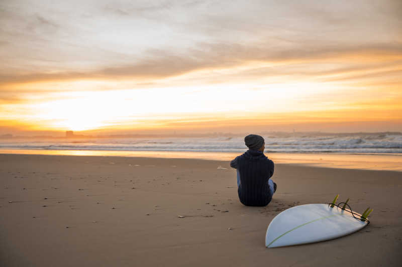日落时分冲浪者坐在沙滩上看海