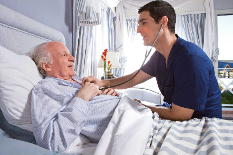 男护士正在用听诊器检查老人肺部