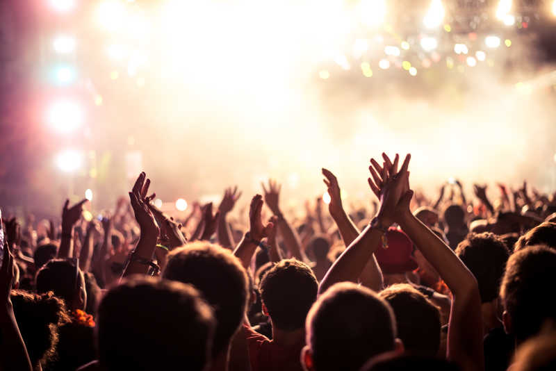 在音乐会上举起手来的歌迷和舞台上方的灯光