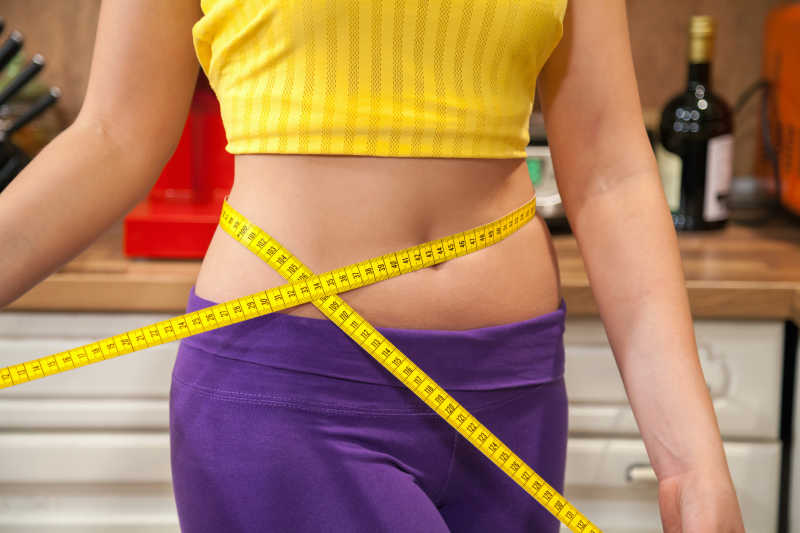  用皮尺测量腰围的女性测量腰围