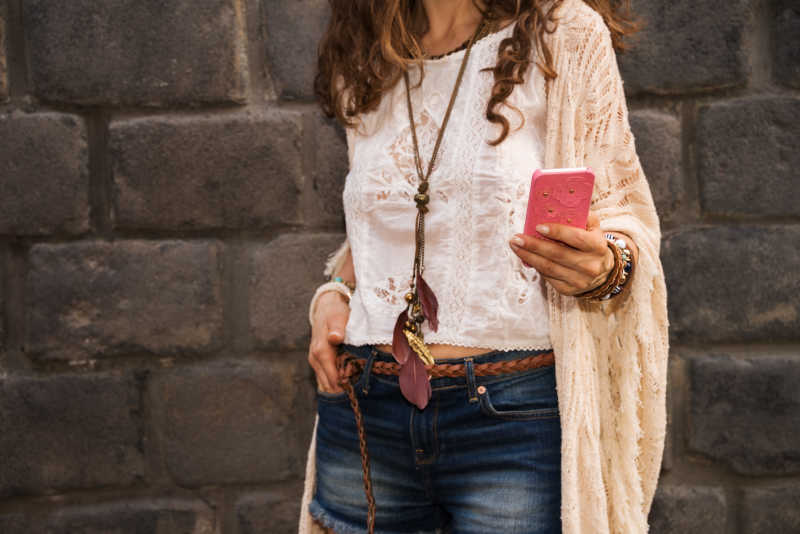 时尚年轻女子在古城墙附近玩手机