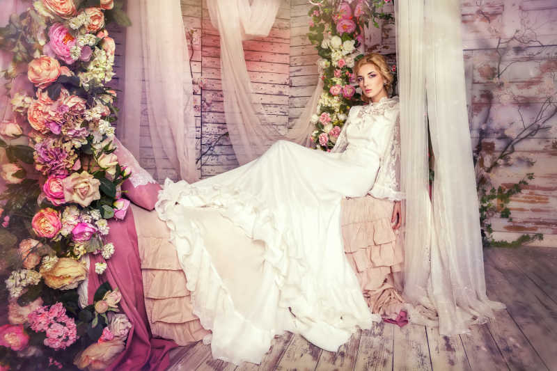 美丽的新娘坐在布置了鲜花的床上