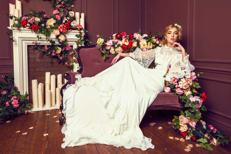 年轻漂亮的新娘坐在布满鲜花的沙发上