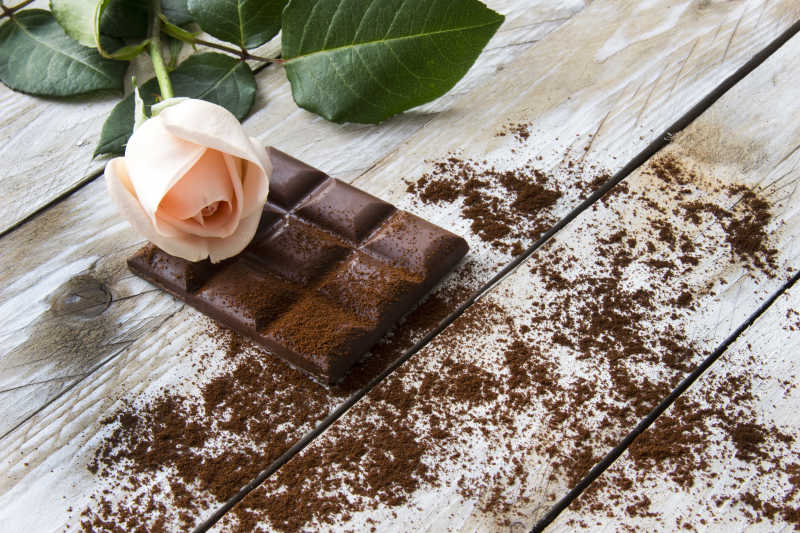 桃色玫瑰和木桌上的巧克力片