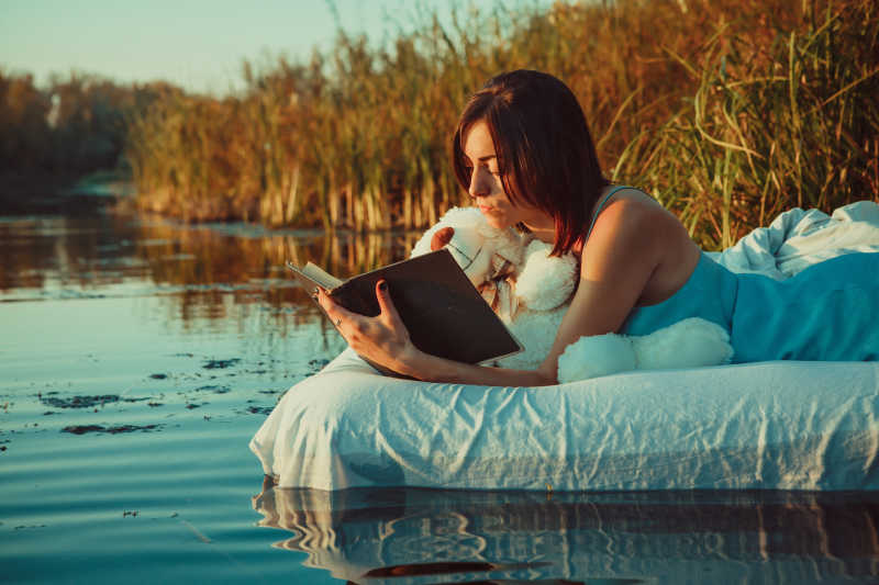 在夕阳下的湖面上看书的女孩