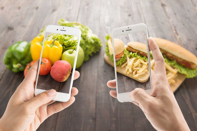 正在拍健康食品和垃圾快餐的智能手机