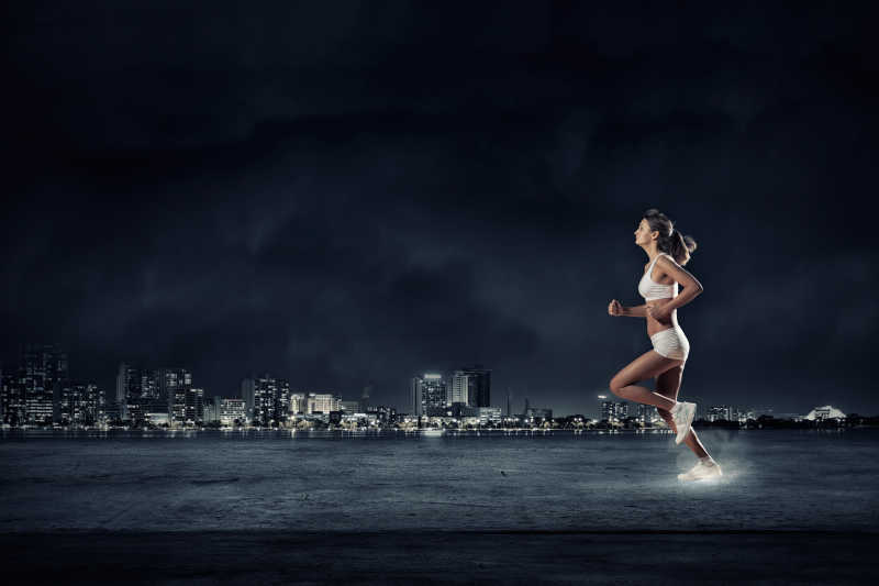 城市夜色下跑步的女运动员