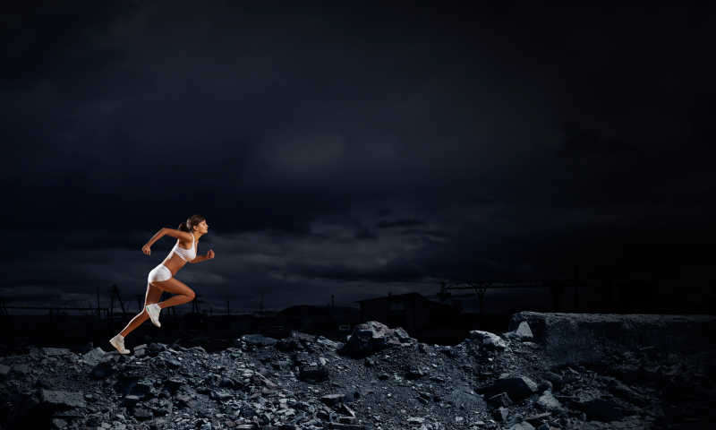 夜色下的美女运动员全速跑步