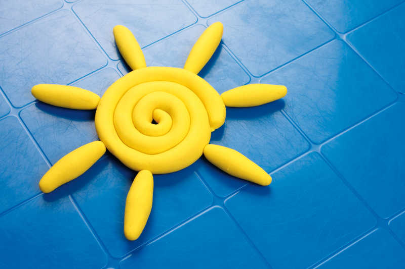 蓝色地板上用黄色橡皮泥制作的太阳图案