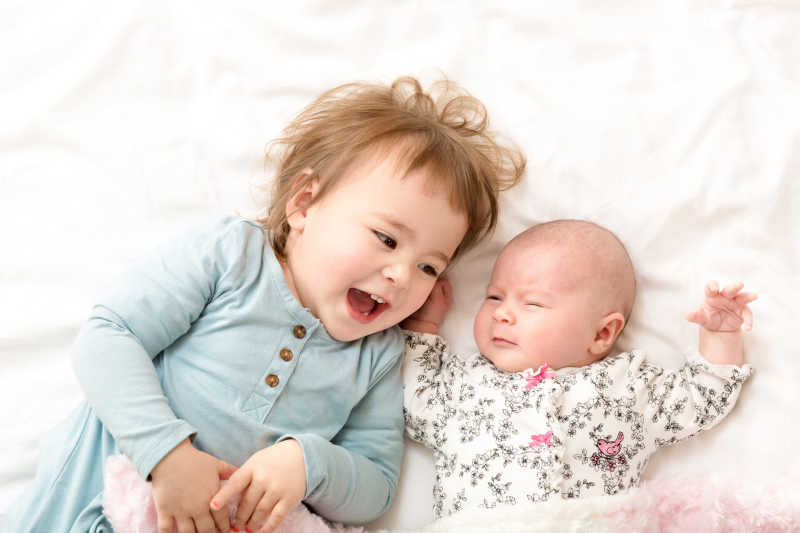 快乐的女孩和她的新生妹妹睡在一起
