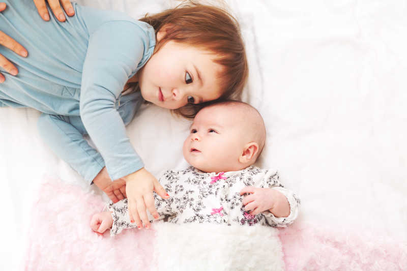 可爱的小女孩和她的新生妹妹睡在一起