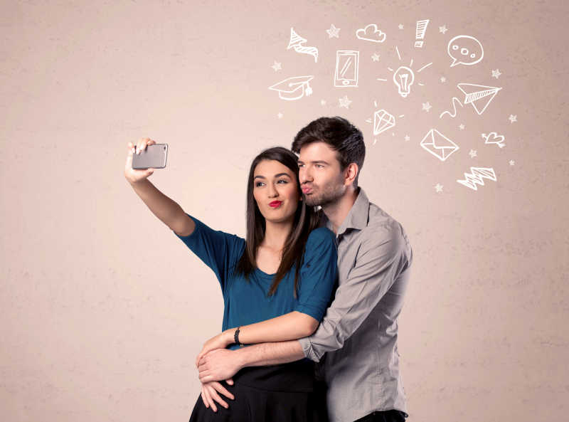 在帅哥的手手机吸引媒体传播图标上面的爱自拍一对年轻夫妇