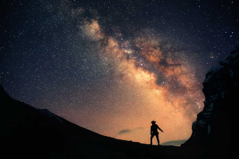 一个男人正站在银河系的旁边