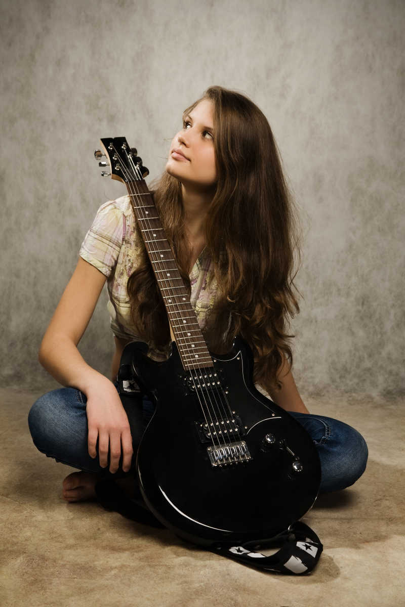 抱着吉他坐在地上的少女