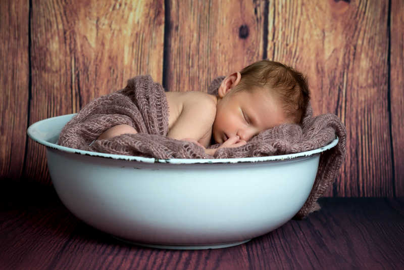 可爱的盆子里盖着毛毯的婴儿