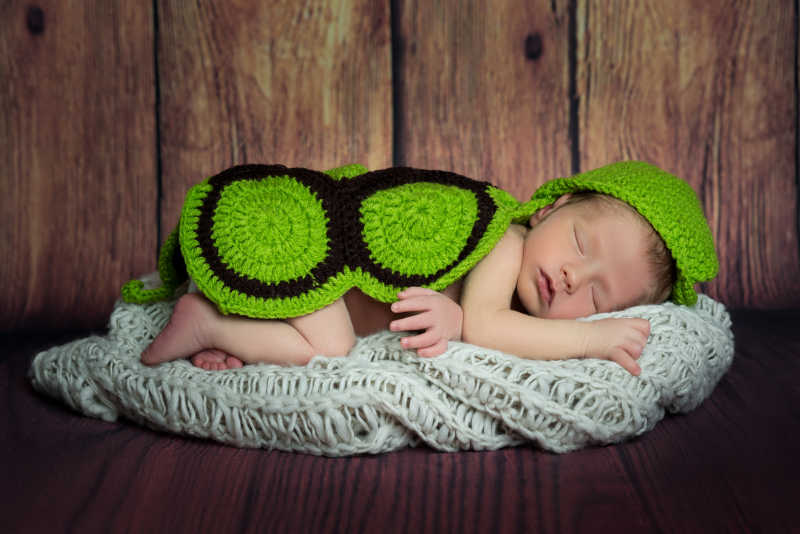 披着绿色花纹毛毯的睡着的婴儿
