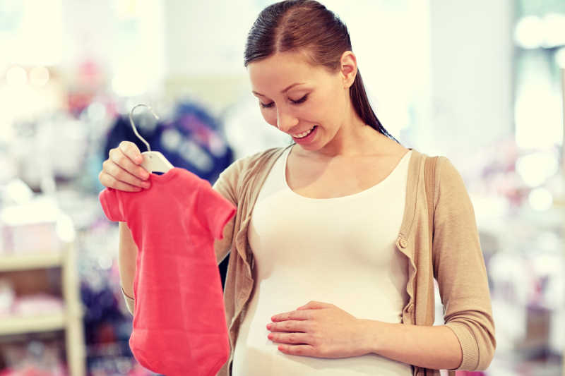 在服装店挑选衣服的孕妇