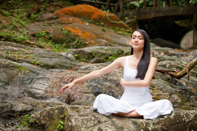 美丽的亚洲女子在户外天然林练习瑜伽