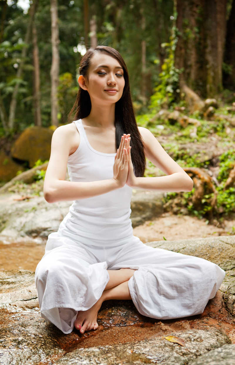 在户外天然林练习瑜伽的美丽的亚洲女子