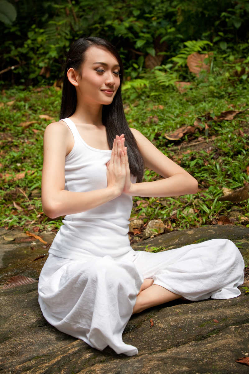 在户外的自然森林里练习瑜伽的亚洲女子