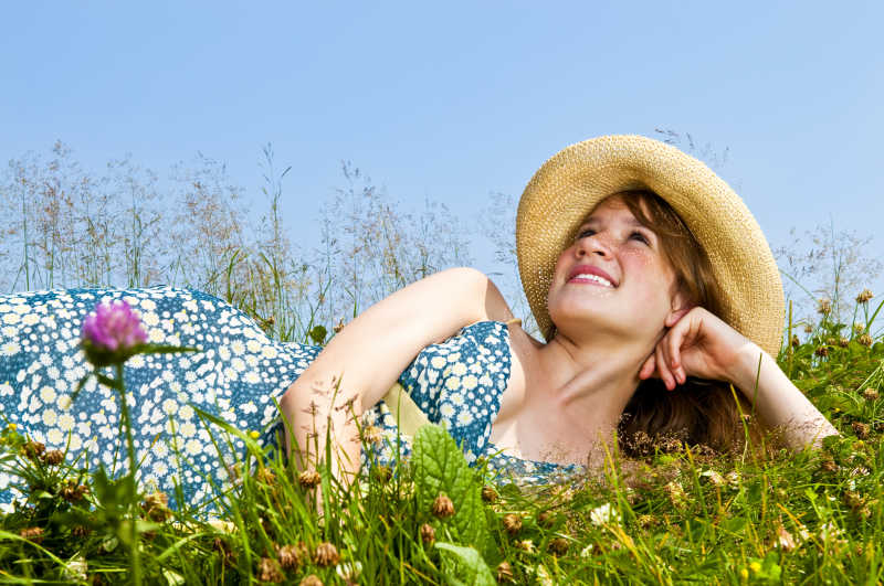 戴草帽的少女躺在夏日草甸上