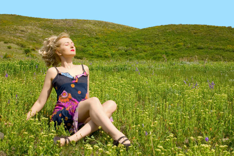美丽的女人坐在草地上放松