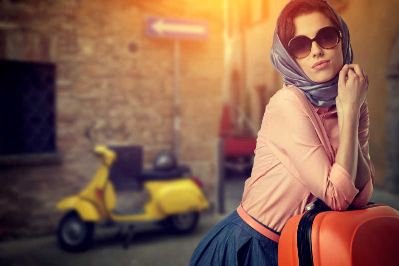 意大利城市街道上带着橙色旅行箱的女人