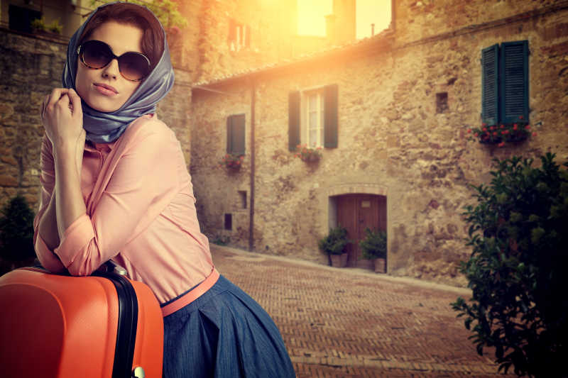 意大利城市街道上带着一个旅行箱的女人