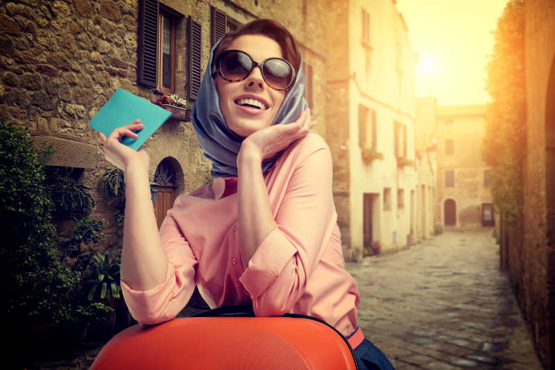 优雅的女人带着行李箱和机票在意大利城市街头