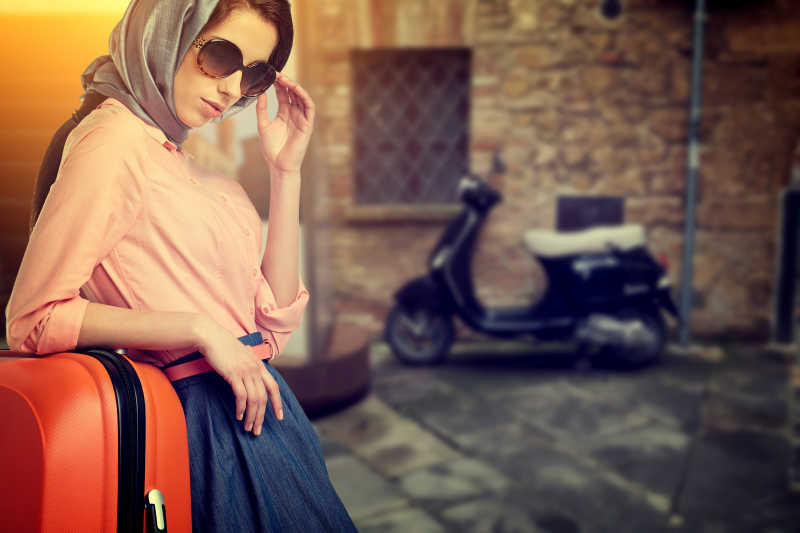 意大利城市街道上带着橙色的旅行箱的女人