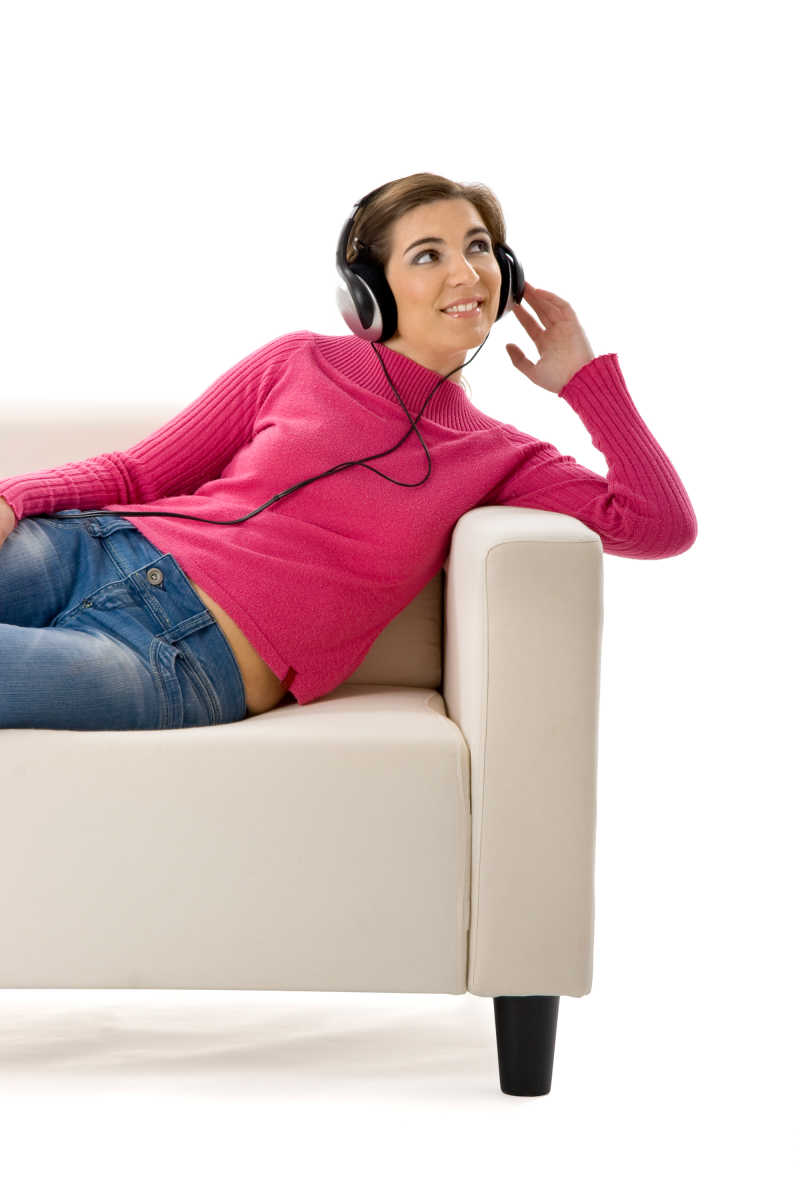 年轻女子在沙发上用耳机听音乐