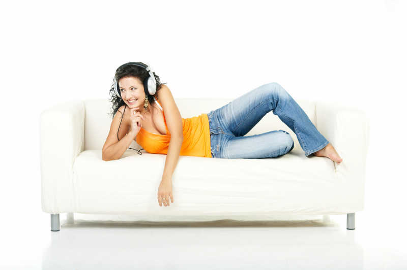 在沙发上带耳机听音乐的女孩