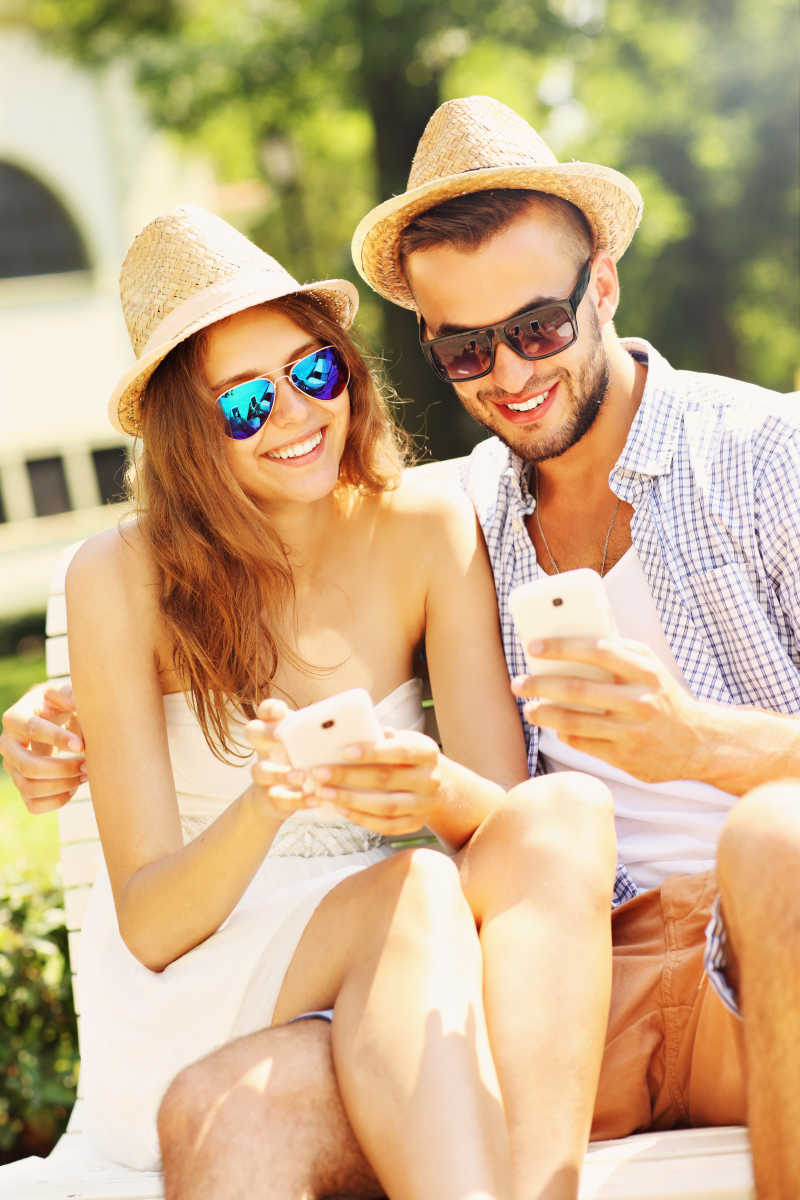 快乐情侣坐在板凳上用智能手机