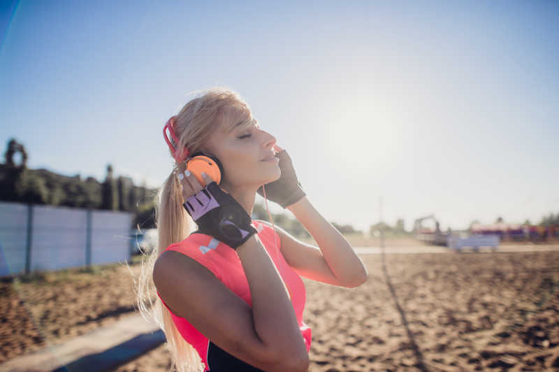 美丽的年轻金发女子在沙滩上听音乐