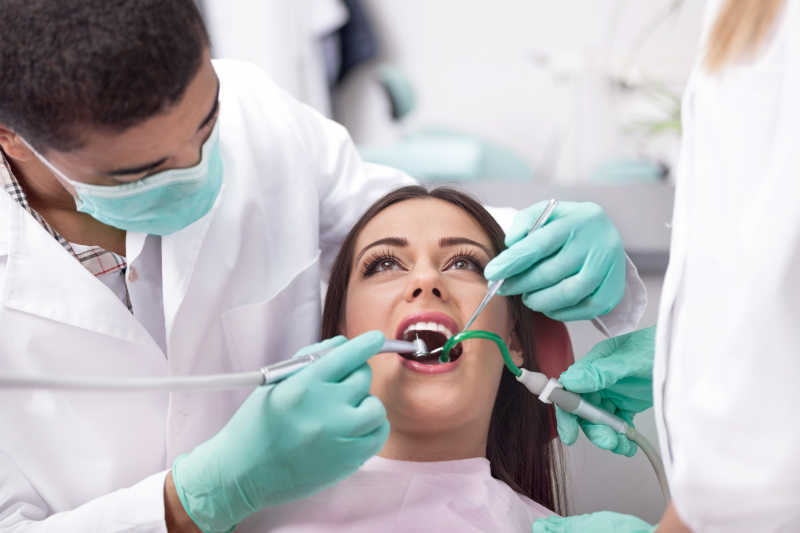 正在治疗女性患者的牙齿的牙科医生