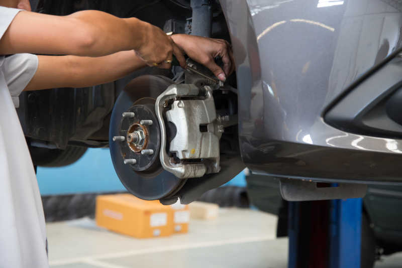 汽车修理厂里机械手更换灰色汽车车轮