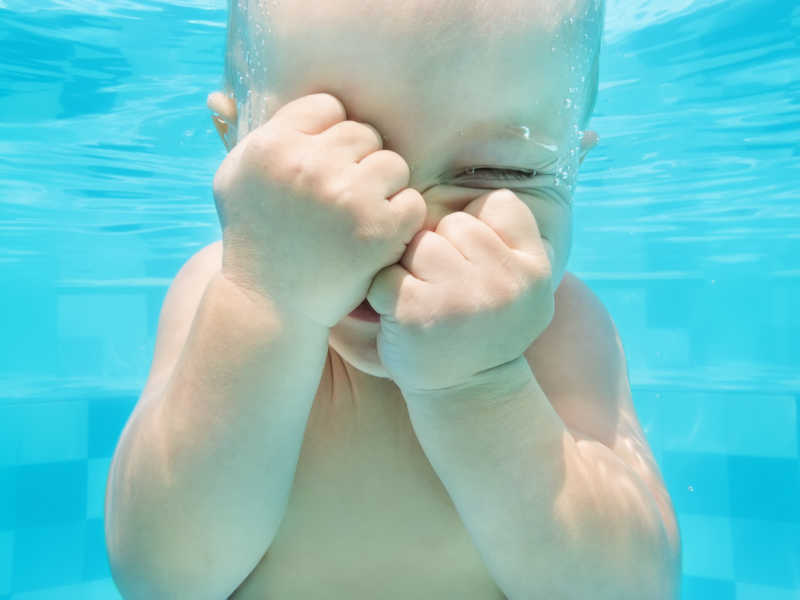 滑稽的婴儿在水中游泳和潜水的照片